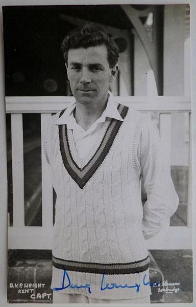 An original half-length postcard photograph of Doug Wright, standing with his arms behind his back.