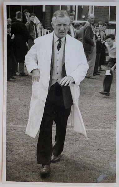 An original full-length postcard-size photograph of D.E. Davies, with umpire's coat.